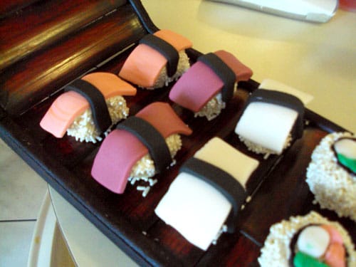 sushi cupcakes that look like rice balls with fondant \"fish\" laid over them