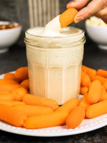 hand dipping a carrot into cashew ranch dressing