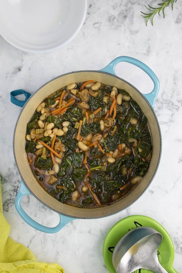 kale and bean soup in a Dutch oven on a marble table