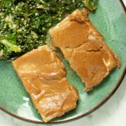 overhead photo of baked tofu with peanut sauce on a plate with ginger kale