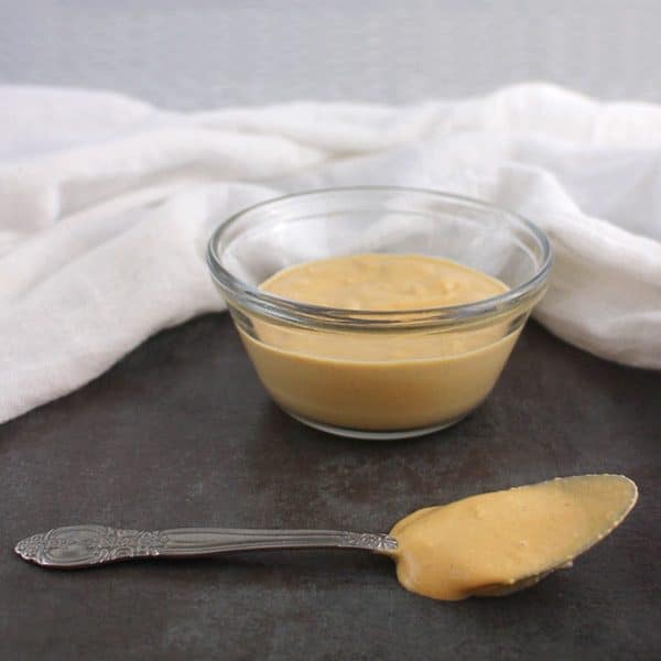 magical tahini dressing in a bowl with a serving spoon next to it