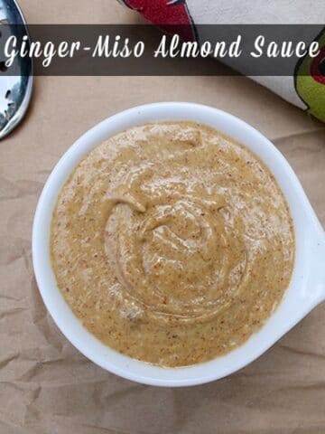 overhead photo of ginger miso almond sauce in a small bowl with a text overlay