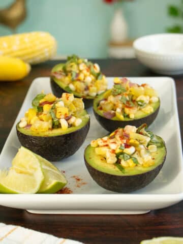 stuffed avocados with corn and summer squash on a wooden table