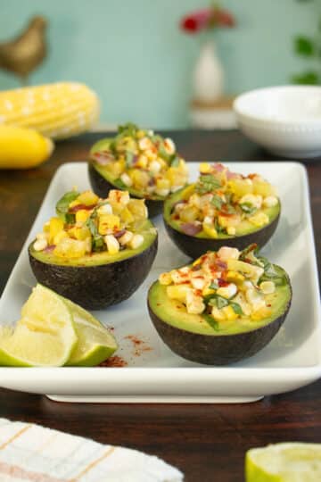 stuffed avocados with corn and summer squash on a wooden table