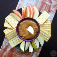 overhead photo of peanut butter dip on a serving platter with apple slices and crackers for dipping