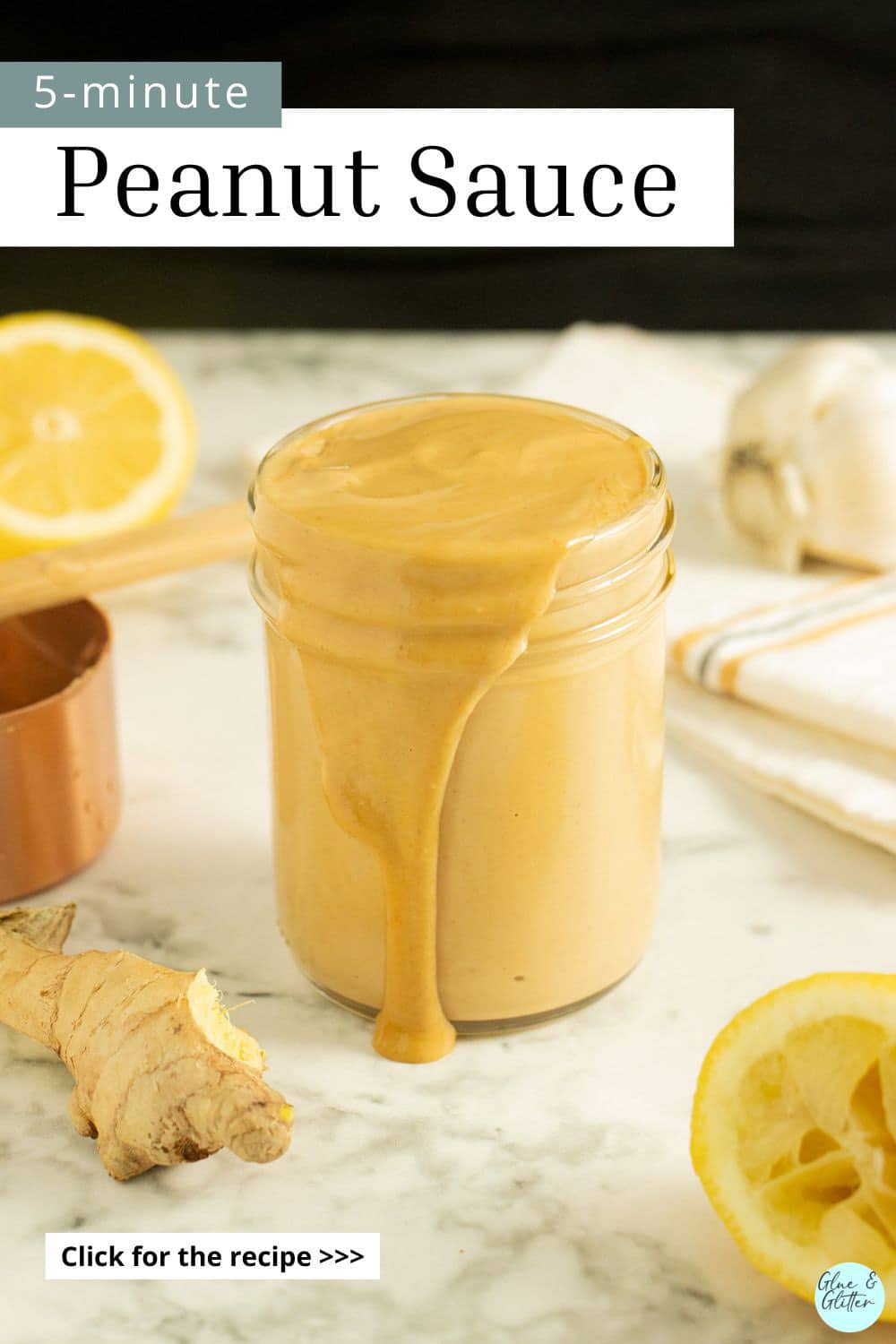 jar of ginger peanut sauce on a marble table surrounded by ingredients, text overlay with recipe title on it