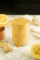 jar of ginger peanut sauce on a marble table surrounded by ingredients