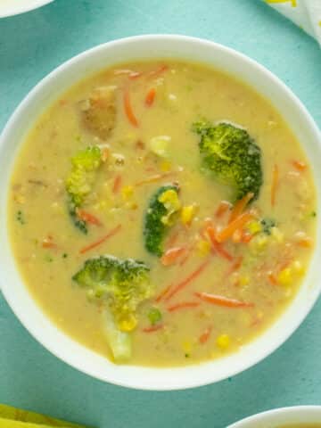 A bowl of vegan corn chowder with broccoli and carrots on a table