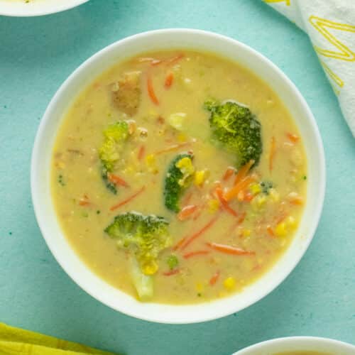A bowl of vegan corn chowder with broccoli and carrots on a table