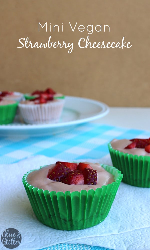 white serving plate of miniature vegan strawberry cheesecakes garnished with sliced strawberries, text overlay