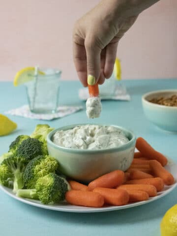 dipping a carrot into ranch party dip so you can see how thick and creamy it is
