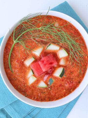 overhead photo of watermelon gazpacho in a white bowl garnished with watermelon and cucumber