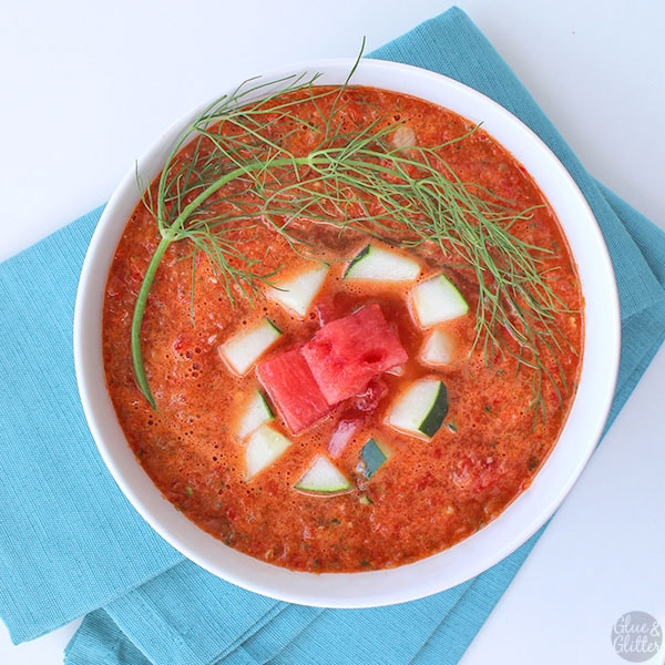 overhead photo of watermelon gazpacho in a white bowl garnished with watermelon and cucumber