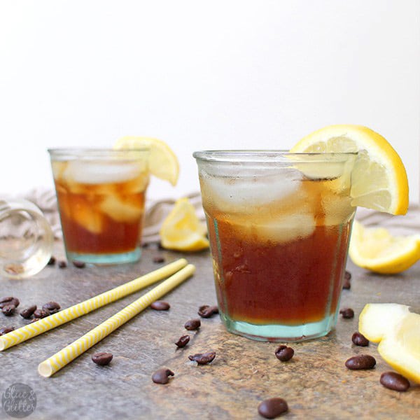 glasses of hard iced coffee lemonade on a table with yellow straws and lemon wedges