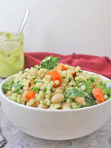 Israeli couscous salad with white beans and a mix of raw and lightly steamed veggies in homemade, creamy avocado-lemon dressing.