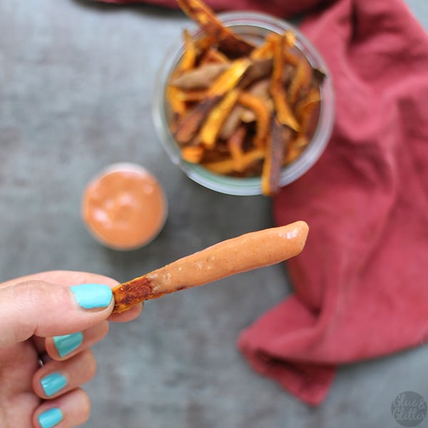 close-up of a hand holding a sweet potato fry dipped creamy sauce