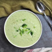 overhead photo of vegan cream of broccoli soup with steamed broccoli garnish