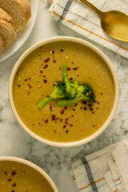 bowl of creamy vegan broccoli soup topped with steamed broccoli and red pepper flakes