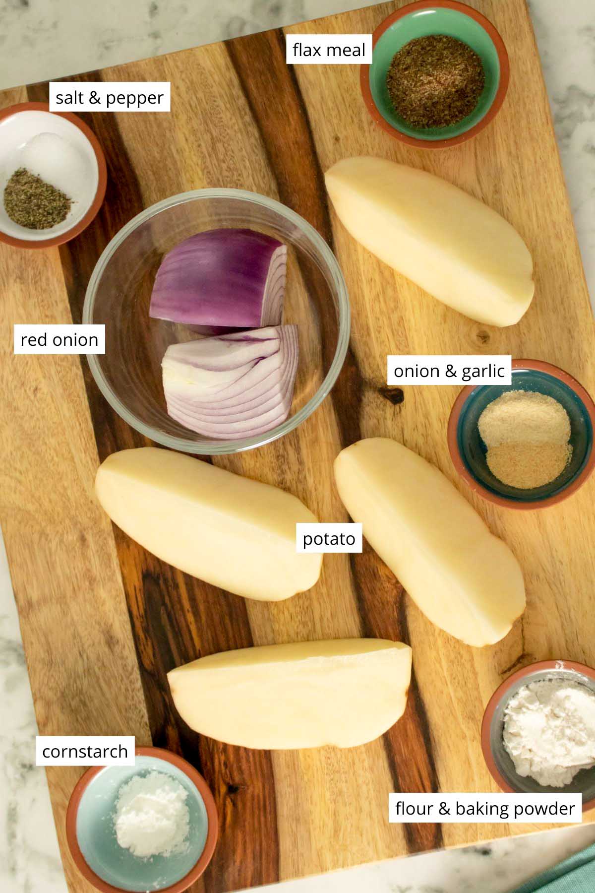 peeled, quartered potato and pieces of onion with seasonings and other dry ingredients on a cutting board with text labels
