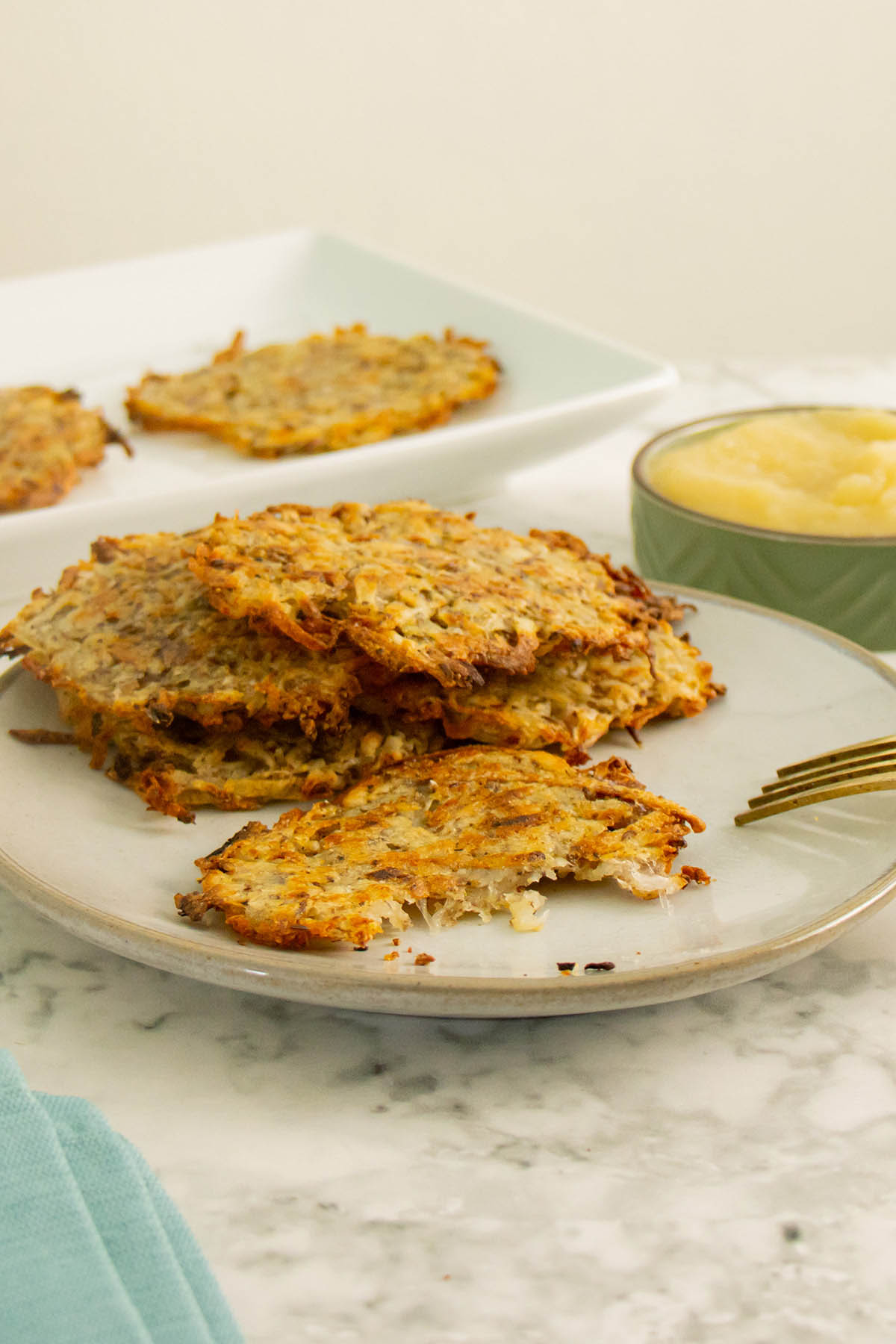 stack of vegan latkes on a plate with a bite taken out of one, so you can see inside