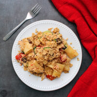 A plate of vegan rigatoni casserole, topped with crushed rice crackers