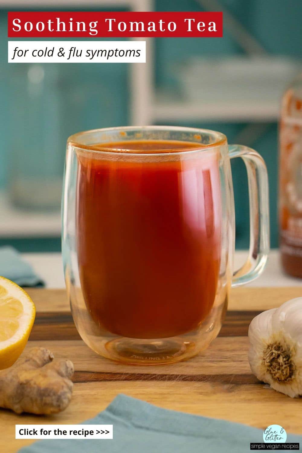 mug of tomato tea on a wooden countertop with ginger, garlic, lemon, and hot sauce around it, text overlay
