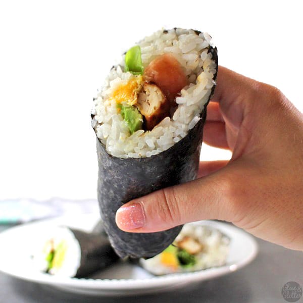 hand holding a sushi burrito, so you can see the rice and fillings