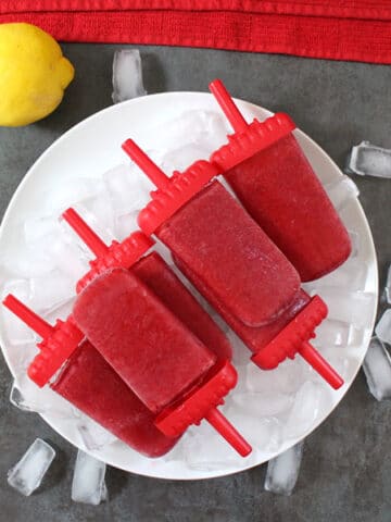 pile of cherry-lemon smoothie pops on a plate of ice cubes