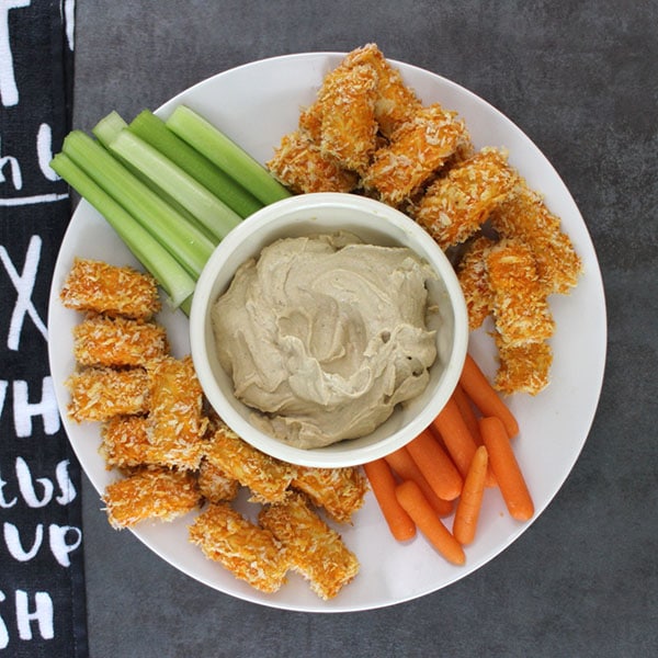 spicy tofu bites on a serving tray with carrots, celery, and Dilly Tahini Sauce