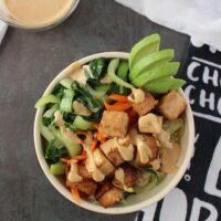 overhead photo of tofu bowl with vegetables on a gray table