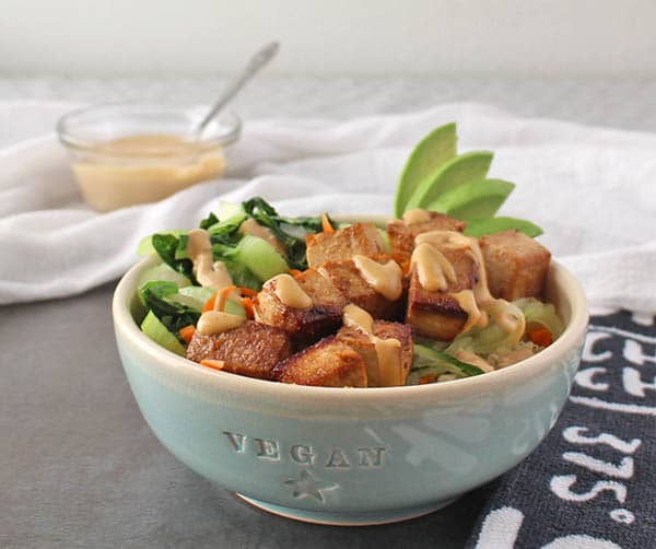vegan baked tofu bowl with vegetables and sauce in a bowl