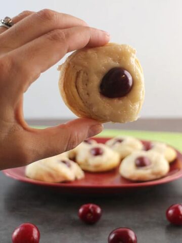 hand holding a mini vegan Danish with a cherry in the middle