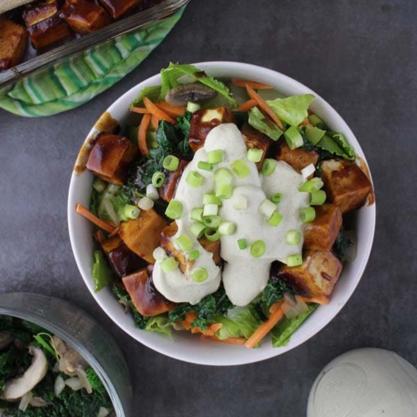 overhead photo of a bowl of warm romaine salad with BBQ tofu and tahini ranch dressing