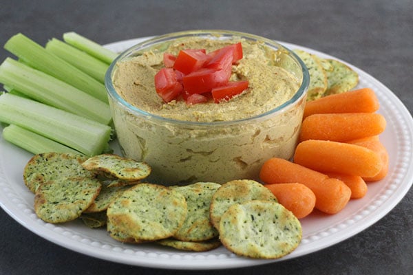 close-up of a bowl of sunflower pate with carrots, celery, and crackers