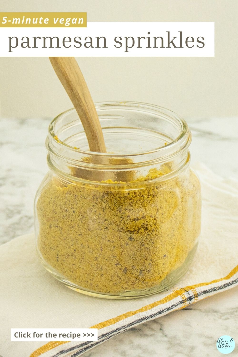 glass jar of vegan parmesan cheese with a wooden scoop in it, text overlay