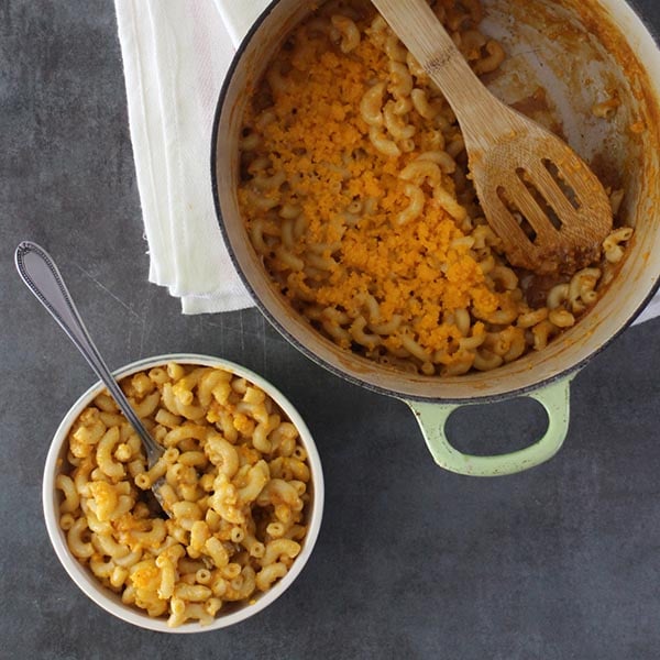 overhead photo of vegan mac and cheese in a bowl next to the serving dish
