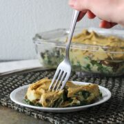 taking a bite of vegan potatoes au gratin with collards on a small plate