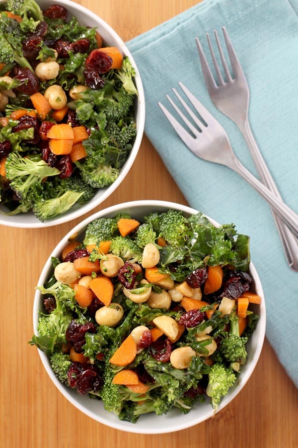 big bowls of kale broccoli salad with a blue napkin and forks