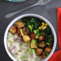 overhead photo of a vegan mashed potato bowl with tofu, kale, corn, and green onions