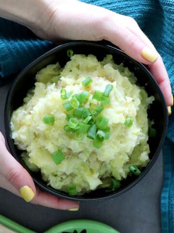hands holding a bowl of vegan colcannon