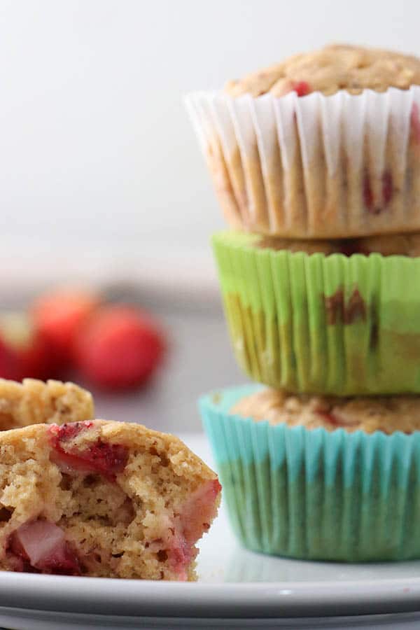 strawberry muffin pulled apart with a stack of muffins in the background