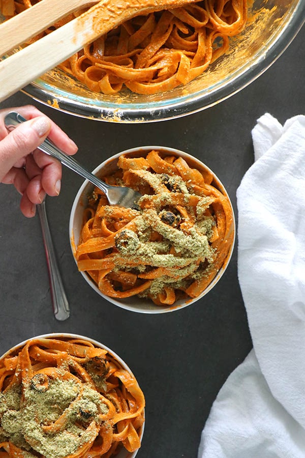 Bowls of vegan pesto pasta with a sprinkle of vegan parmesan cheese on top