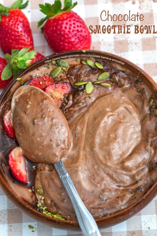 overhead photo of a vegan peanut butter smoothie bowl with a spoon and sliced strawberries