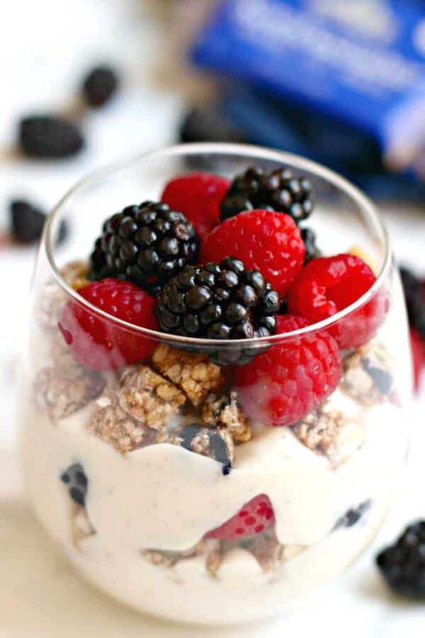 a glass of vegan yogurt layered with granola and fresh berries
