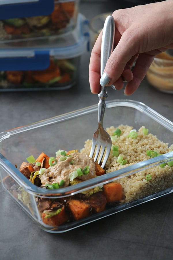 Close-up of fork getting a bite from a meal prep container with peanut sauce