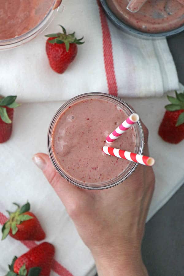 hand picking up a glass of strawberry tahini smoothie