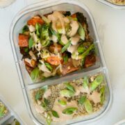 sweet potatoes and Brussels sprouts in a meal prep container with quinoa, sauce, and green onions