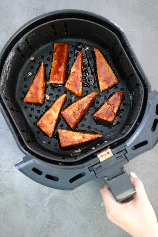 tofu triangles coated in BBQ saice in an air fryer basket
