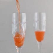 straining a strawberry French 75 into a glass