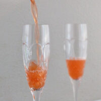 straining a strawberry French 75 into a glass